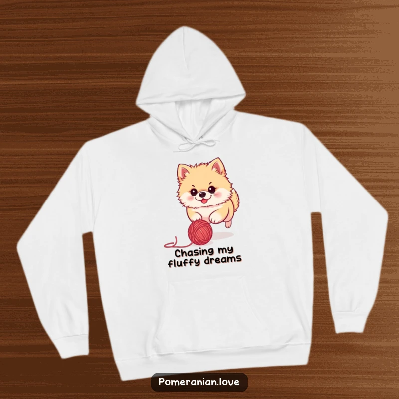 Funny Pomeranian hoodie showing a cute dog with laser focus, enthusiastically pursuing a stray ball of yarn. A delightful design for pet owners.